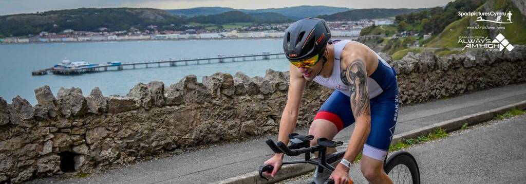 Cyclist on Marine Drive with Llandudno Pier in the background.