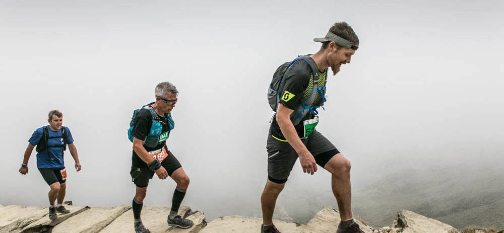 Three runners ascending the PyG Track of Snowdon in the Snowdonia Trail Marathon, Wales