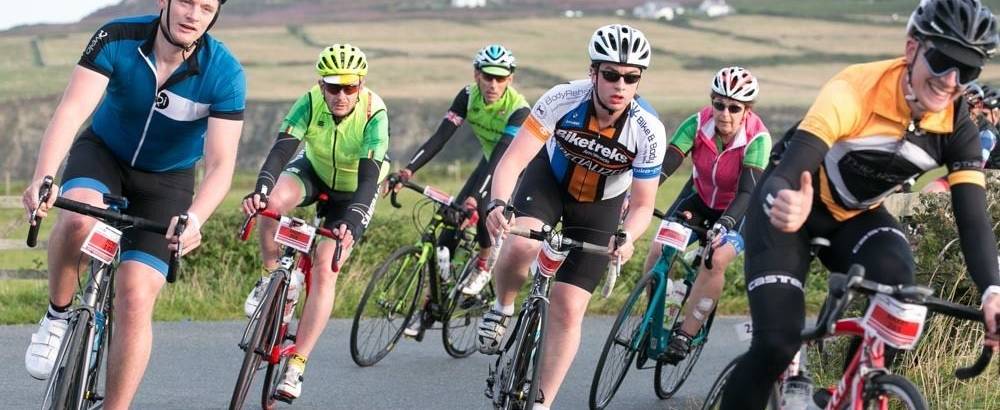 A group of riders on a swooping left behind in the Tour de Mon Anglesey Cycle Sportive